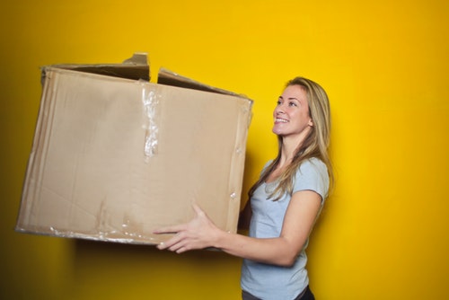 woman-in-grey-shirt-holding-brown-cardboard-box