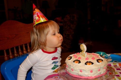 2nd birthday child blowing a Dora cake